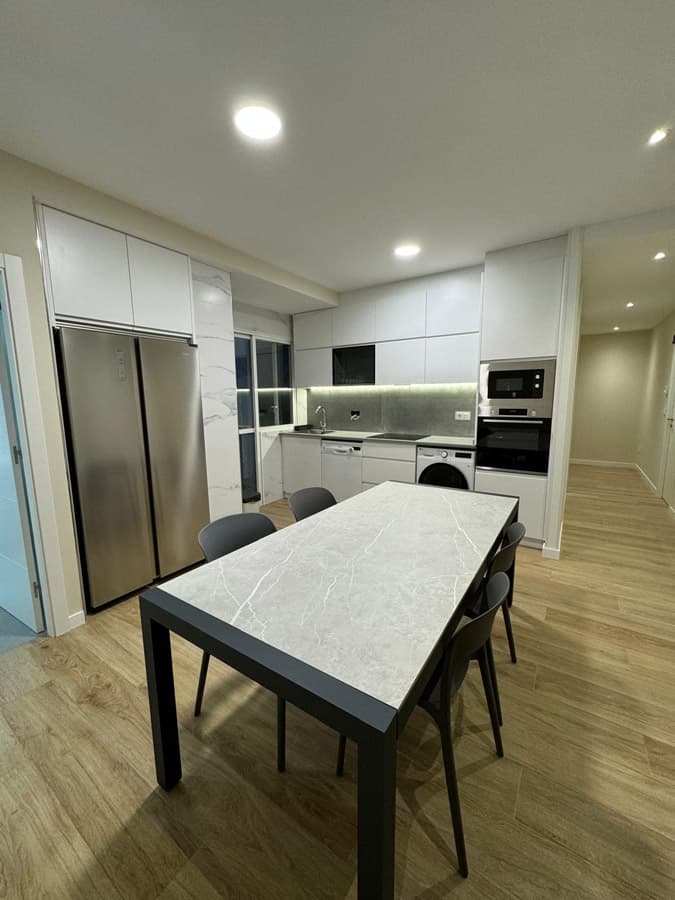 Cocina a medida en Ames en blanco con mesa de comedor y frigorífico americano